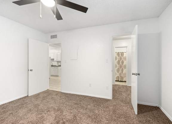 A room with a ceiling fan and carpeted floor.