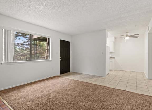 A room with a brown carpet and a ceiling fan.