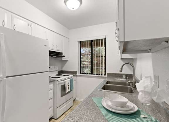A white kitchen with a refrigerator, oven, and sink.