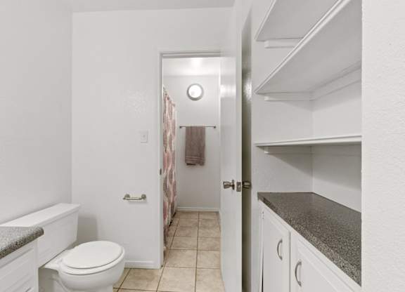 A white toilet sits in a small bathroom next to a white bathtub.