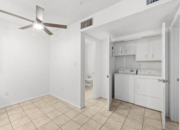 A white room with a fan and a bathroom with a toilet and sink.