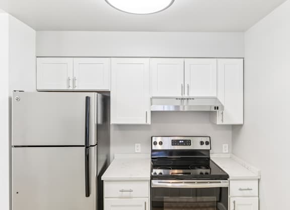 A white kitchen with a refrigerator, oven, and cabinets.