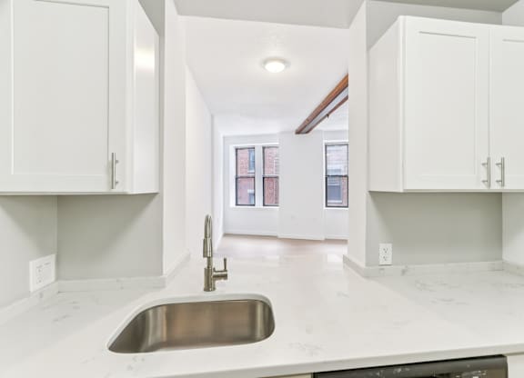 A kitchen with white cabinets and a marble countertop.
