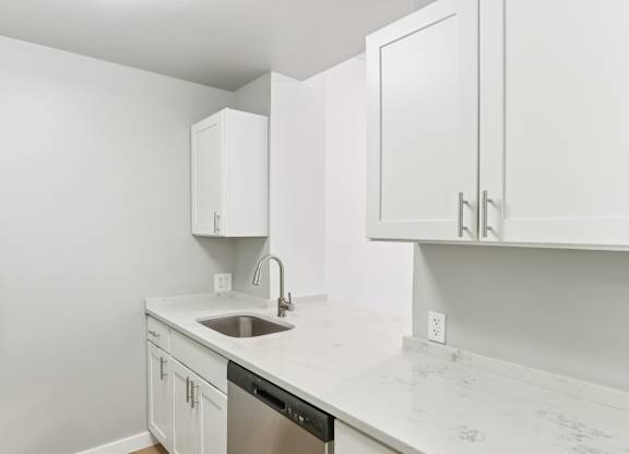 A kitchen with white cabinets and a marble countertop.