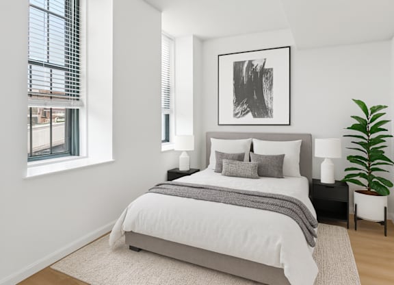 A bedroom with a large bed, a potted plant, and a framed picture on the wall.