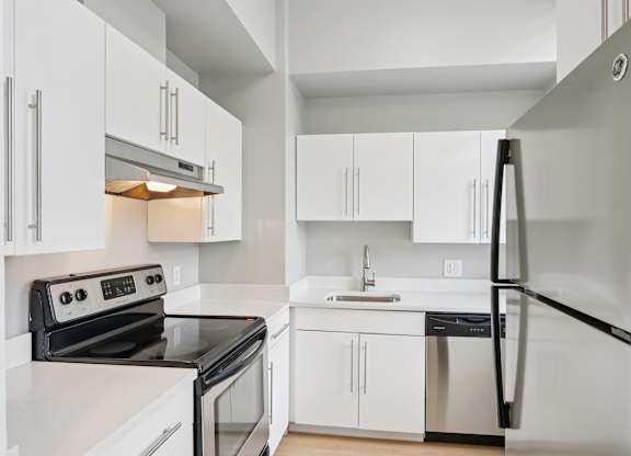 A modern kitchen with white cabinets and stainless steel appliances.