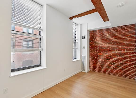 A room with a red brick wall and wooden flooring.