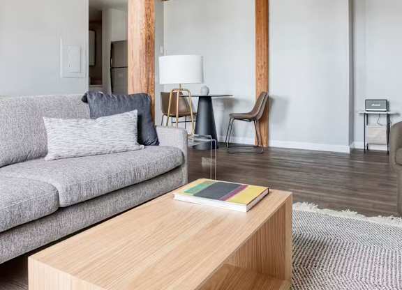 A living room with a grey couch, a wooden coffee table, and a lamp.