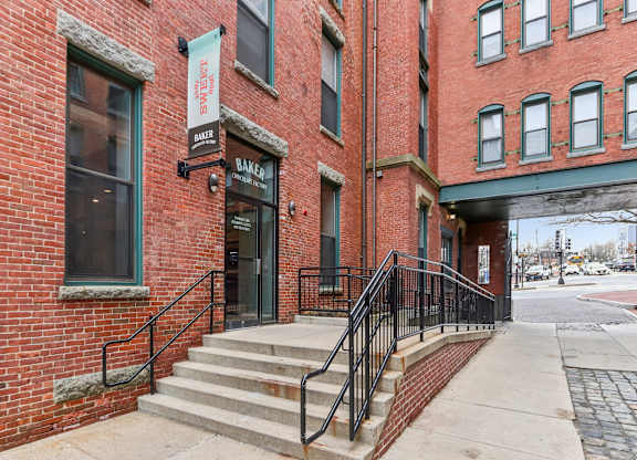 A red brick building with a black railing on the stairs.