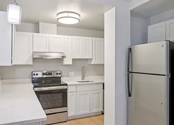 A kitchen with white cabinets and a black refrigerator.