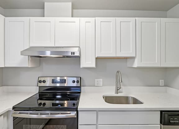 A modern kitchen with white cabinets and a stainless steel stove.