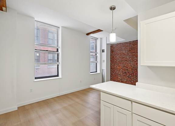A kitchen with white cabinets and a brick wall.
