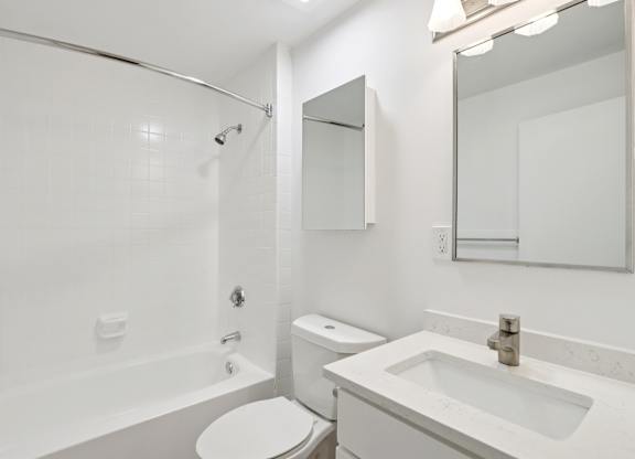 A white bathroom with a toilet, sink, and bathtub.
