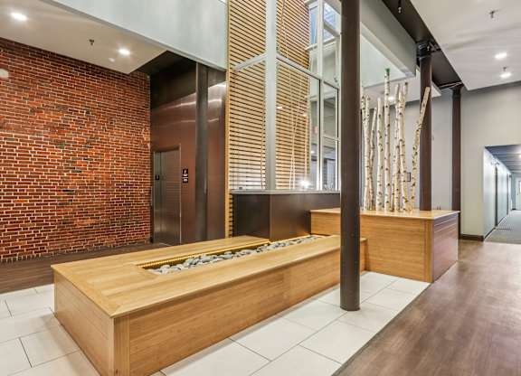 A long wooden table with chairs is in the middle of a room with a brick wall.