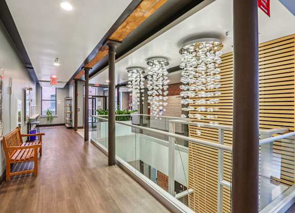 A long hallway with a wooden bench and a chandelier hanging from the ceiling.