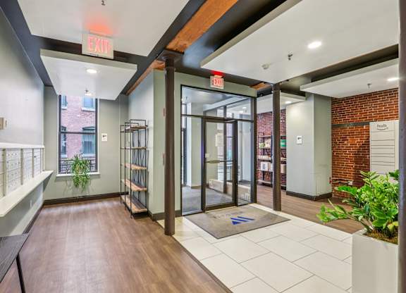 A hallway with a bench, a plant, and a door with a glass panel.