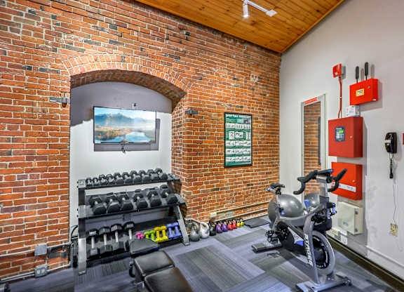 A gym with a brick wall and a row of dumbbells.