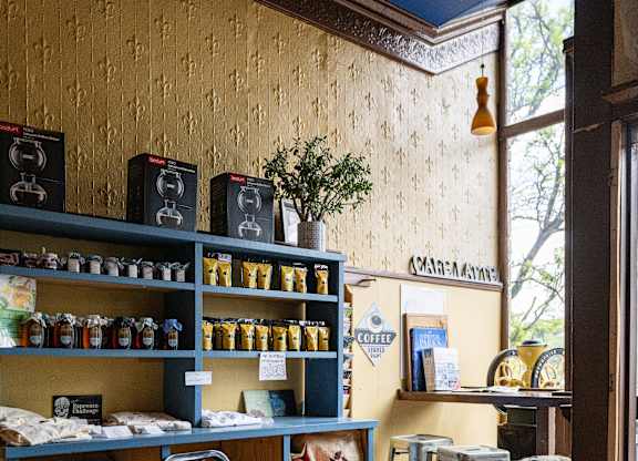 A coffee shop with shelves of coffee products and a sign that says "Coffee".