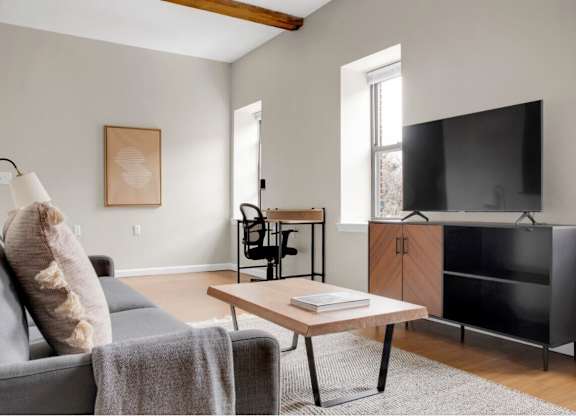 A living room with a grey couch, a wooden coffee table, and a black entertainment center.