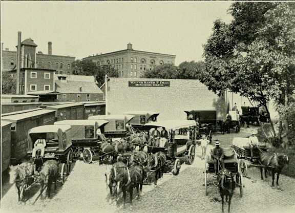 A black and white photo of a horse-drawn carriage street.