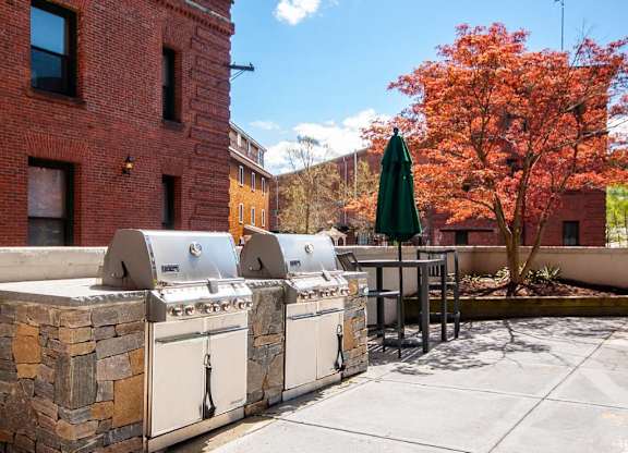 A row of outdoor grills are lined up on a patio.