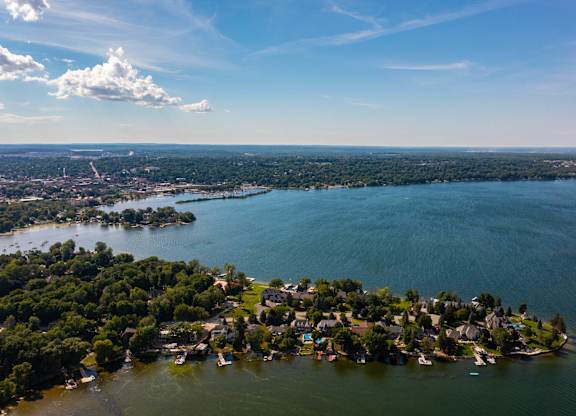 A small island with houses and boats surrounded by water. at The Grove  Apartments, Orillia, ON