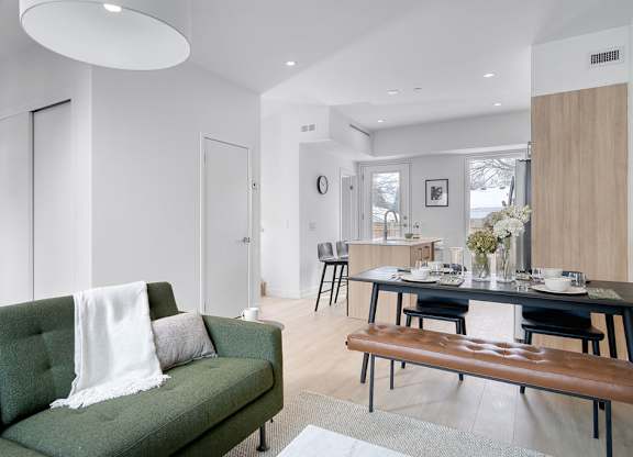 A modern living room with a green couch and a wooden bench at The Grindstone Apartments, Ontario, L0R 2H0