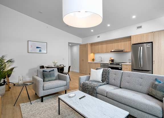 A modern living room with a grey couch and a coffee table at The Grove Apartments, Orillia, Ontario
