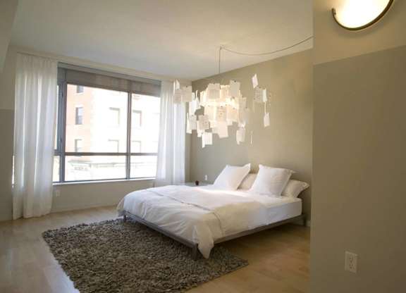 A bedroom with a large bed and a chandelier.at 66 Main, Yonkers