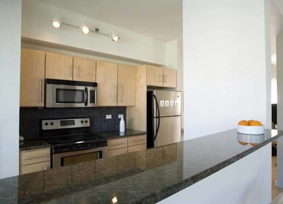 A modern kitchen with a black countertop and stainless steel appliances.at 66 Main, Yonkers New York