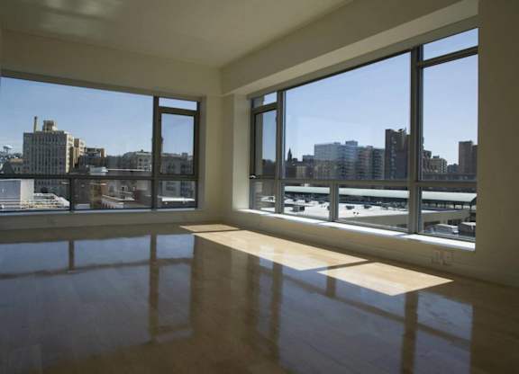 A room with a wooden floor and large windows overlooking a cityscape.at 66 Main, Yonkers