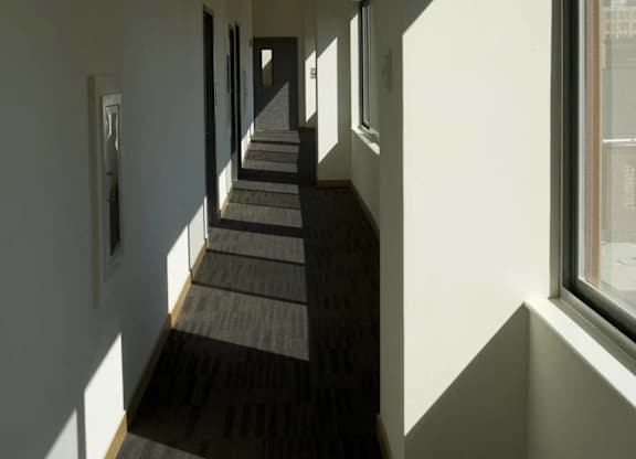 A long hallway with carpeted floors and windows on the side.at 66 Main, Yonkers, NY 10701