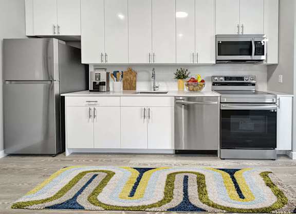 A modern kitchen with white cabinets and stainless steel appliances.