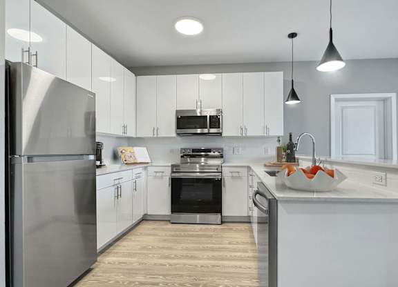 A modern kitchen with white cabinets and stainless steel appliances.
