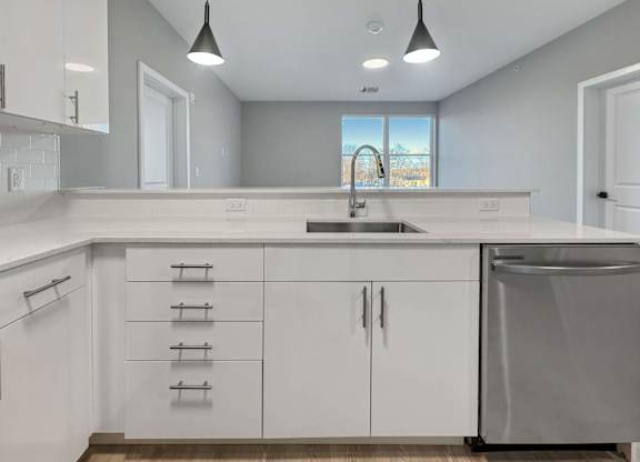 A modern kitchen with white cabinets and a stainless steel dishwasher.