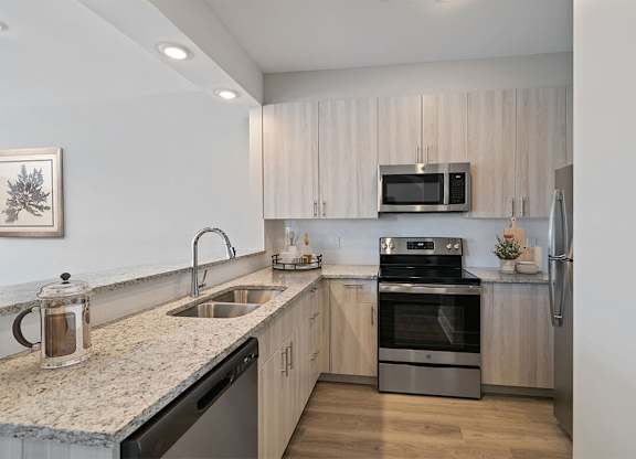 A modern kitchen with a granite countertop and stainless steel appliances.