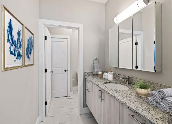 A bathroom with a white door and a mirror above a sink.
