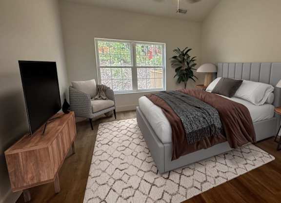 A bedroom with a bed, chair, and a television.