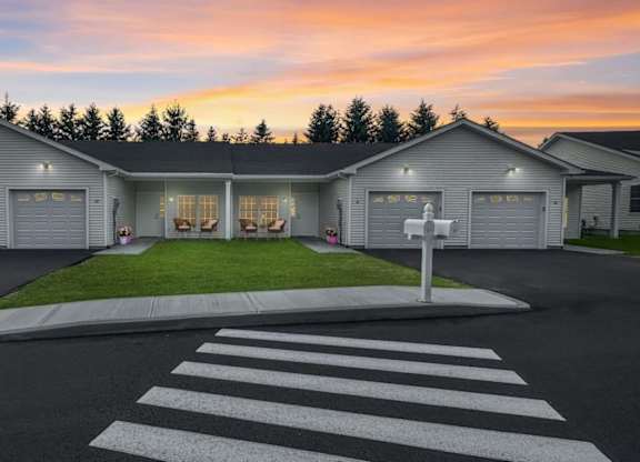 A house with a white garage door is shown with a street in front of it.