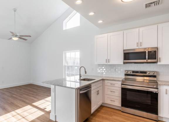 A kitchen with white cabinets and a wooden floor.
