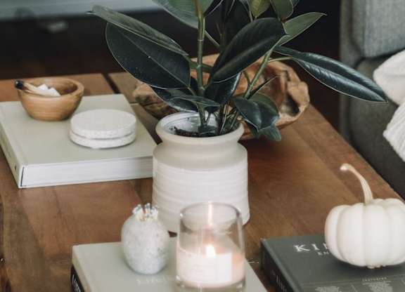 A table with a lit candle, a pumpkin, and a plant.
