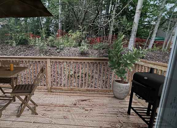 A wooden table with chairs and a potted plant on a wooden deck.