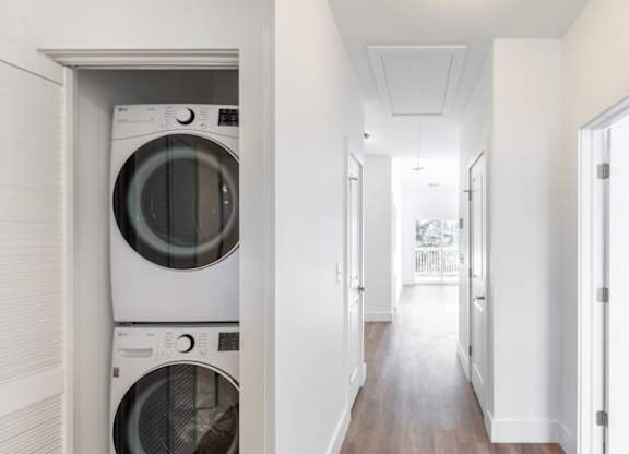 A long hallway with a washer and dryer stacked on top of each other.