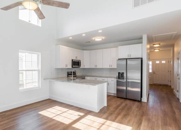 A kitchen with white cabinets and a refrigerator.