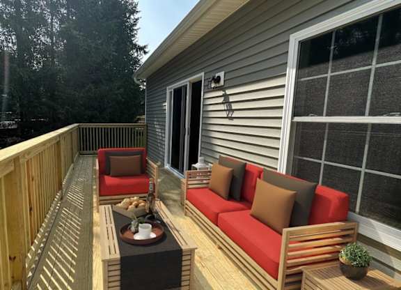 A wooden deck with a red couch and a table.