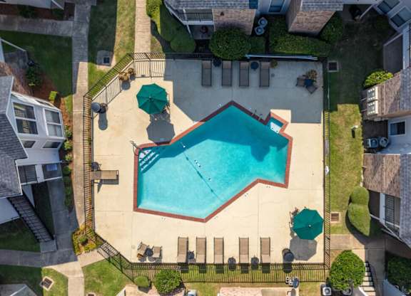 A small pool surrounded by a fence and a few chairs.