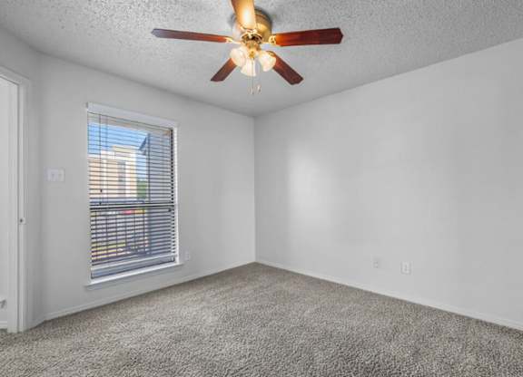 A room with a ceiling fan and a window with blinds.