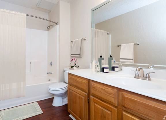A white toilet sits in a bathroom with a wooden vanity and a mirror.