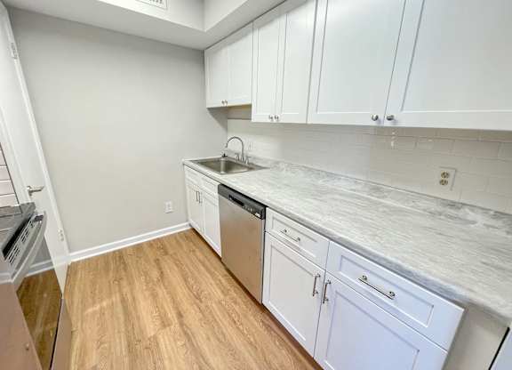 A kitchen with white cabinets and a marble countertop.