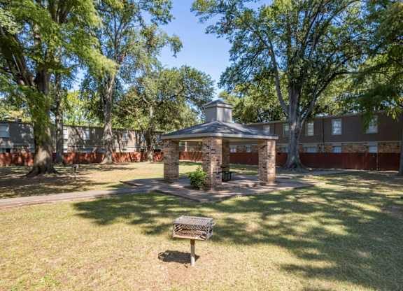 A gazebo is surrounded by trees in a park.